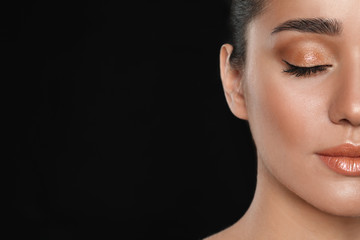 Beautiful young woman with glitter makeup on black background, closeup view. Space for text