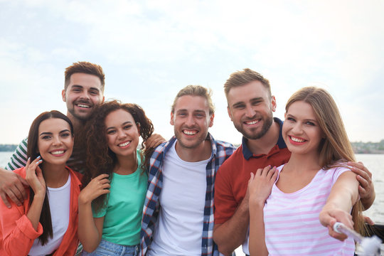 Happy young people taking selfie outdoors on sunny day