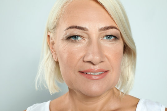 Portrait of mature woman with beautiful face on grey background