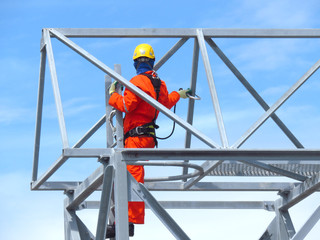 Man Working on the Working at height. Professional industrial climber in helmet and uniform works at height. Risky extreme job. Industrial climbing at construction site.   