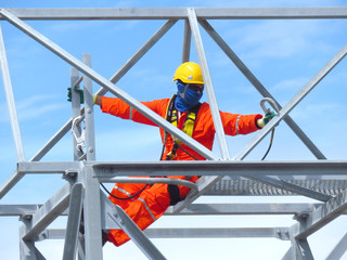 Man Working on the Working at height. Professional industrial climber in helmet and uniform works at height. Risky extreme job. Industrial climbing at construction site.   