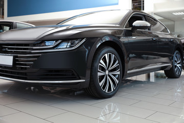 New luxury black car in modern auto dealership, closeup