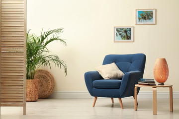 Fototapeta na wymiar Stylish room interior with comfortable furniture and plant near beige wall