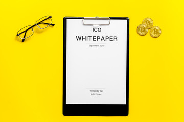 Initial coin offering ICO white paper on yellow background top view