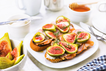 Obraz na płótnie Canvas Served breakfast table. Sliced fig sandwich with ham, cheese and honey.