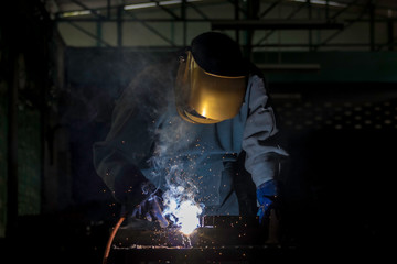 Fototapeta na wymiar A craftman is welding with workpiece steel.Working person About welder steel Using electric welding machine There are lines of light coming out and safety equipment in factory industry.