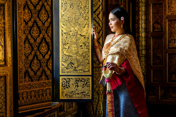 Fototapeta na wymiar Beautiful women Thai girl holding hand Jasmine garland in traditional thai costume with temple ayutthaya is texture gold, identity culture of Thailand.
