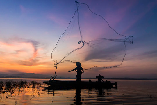 Image is silhouette. Fishermen Casting are going out to fish early in the morning with wooden boats, old lanterns and nets. Concept Fisherman's life style.