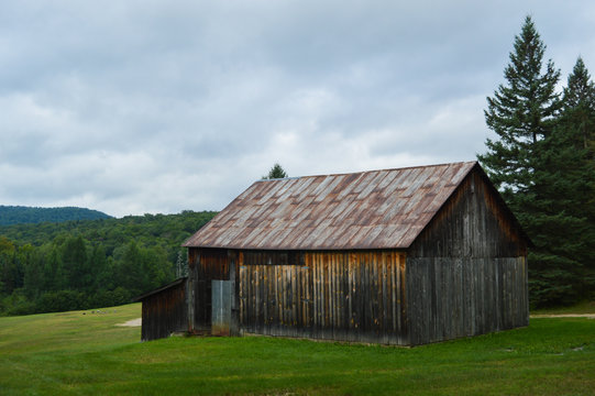 Weather-worn cedar barn overlooking the landscape in the Adirondack Mountains under a troubled sky