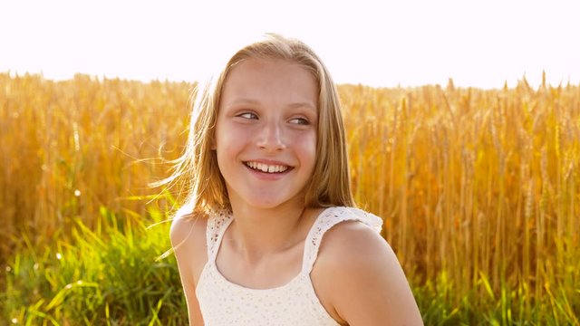 nature and people concept - smiling young girl on cereal field in summer
