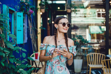 Fototapeta na wymiar young pretty woman posing in the street with phone, outdoor portrait, hipster girls, sisters, chic, tablet, internet, using smartphone, close-up fashion model, post in instagram, facebook