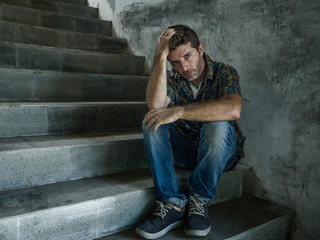 young depressed and sad man sitting alone outdoors on dark street staircase suffering depression problem looking worried thinking and feeling miserable