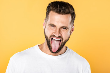 handsome funny man showing tongue isolated on yellow © LIGHTFIELD STUDIOS