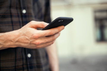 young handsome bearded hipster man using smartphone and listening music with earphones in the city, headphones, sunglasses street, outdoor portrait, cap, hat, concept, hipster male, wall