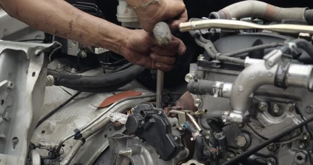 Auto mechanic working on car engine in mechanics garage. car service, repair, maintenance and people concept