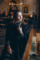 A beautiful girl in a beige jacket drinks coffee from a glass talking on the phone, wearing sunglasses works in the office in the business center, the manager, the employee of the company, happy face