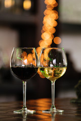 Two glasses of wine white and red standing on a table. Colorful bokeh. Wine tastings, wine tour. Warm toning. Concept alcoholic drinks. 