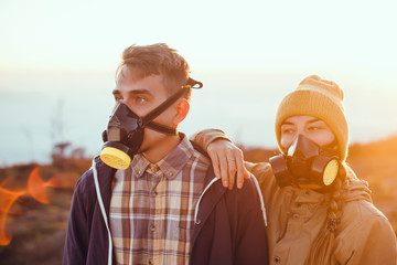 young couple posing on top of a sulfur volcano in respirators and gas masks, Hikers with backpacks relaxing on top of a hill and enjoying view of sunset in ocean. Island Lombok, Indonesia. Traveling 