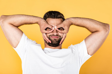 Fototapeta na wymiar smiling funny handsome man in white t-shirt with hands on face isolated on yellow