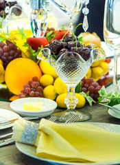 Party dinner table setting with tableware and silverware and glasses set and Candlestick and flower in restaurant.