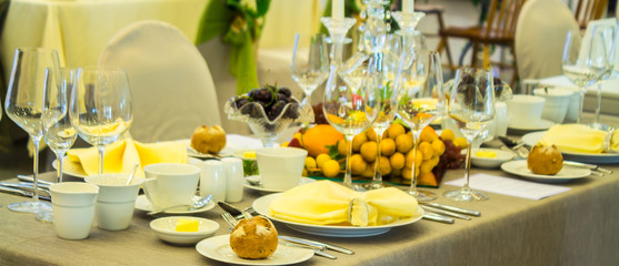 Party dinner table setting with tableware and silverware and glasses set and Candlestick and flower in restaurant.