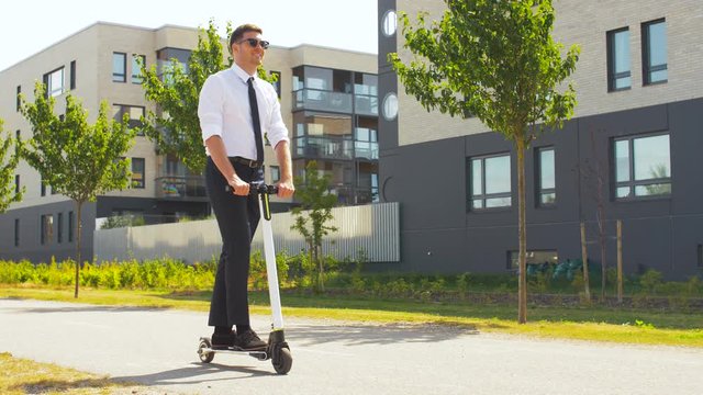 business and people and concept - young businessman riding electric scooter outdoors