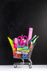 Shopping cart stocked with school supplies and a blackboard