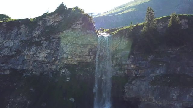 Gorgeous scenic ascending rising view of a waterfall in the mountains against the sun in the background on a beautiful sunny day in sulseewli switzerland