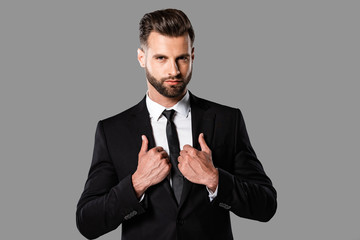 handsome stylish businessman in black suit isolated on grey