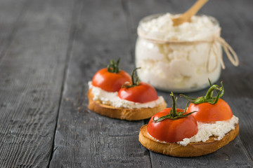 Fried bread, cottage cheese and tomato halves on a wooden table.