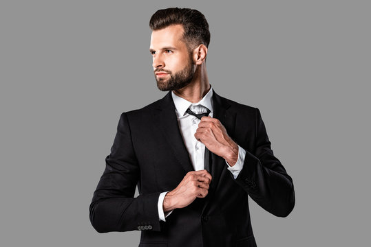 stylish elegant businessman in black suit looking away isolated on grey