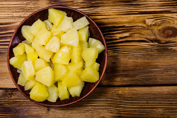 Ceramic plate with chopped canned pineapple on wooden table. Top view