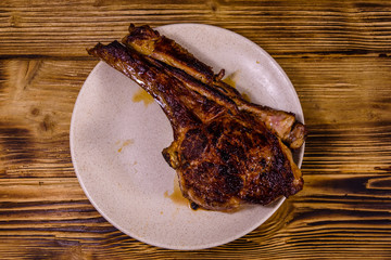 Plate with roasted ribeye steak on wooden table. Top view