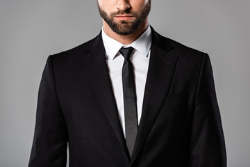 cropped view of serious bearded businessman in black suit isolated on grey