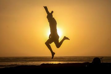 silhouette of a man jumping on the beach at sunset