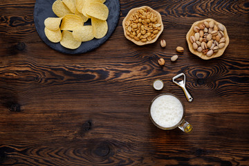 Beer glass with bottle cap and snack on wood background. top view. copy space