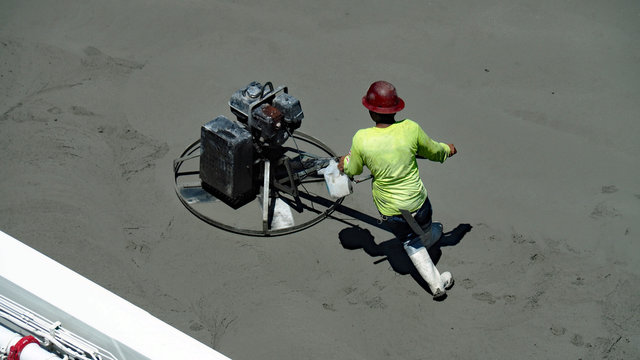 Worker Using Power Trowel To Even The Concrete