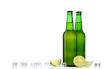 glass beverages with lemon and ice cubes on white background. Green bottle of beer or soda. copy space