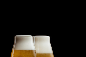two glasses of cold golden beer isolated on a black background. copy space