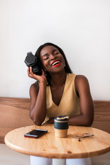 Smiling black girl listening to music on smartphone at cafe.