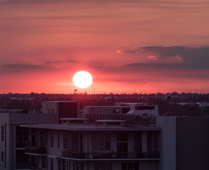 Red sunset sun hiding behind city