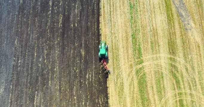 Aerial view drone of harvest field with tractor mows dry grass. Autumn yellow field with a haystack after harvest top view. Harves. Ting in the fields. 