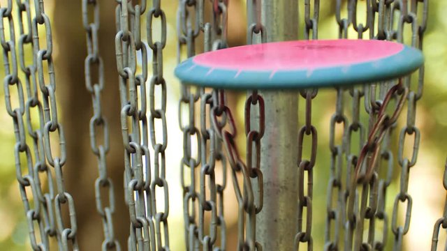 Disc golf basket, closeup of chains, struck by disc, slow motion
