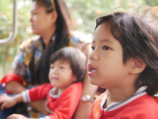 Little Asian baby girl, 26 months old, enjoys taking an open-air truck and having the wind on her face for the first time - allowing the child to have new experience