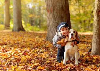 Little girl with beagle outdoors in the autumn park.