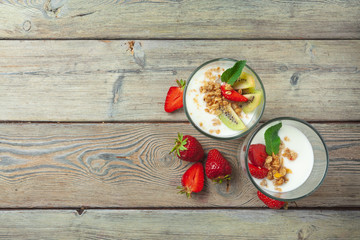 Healthy breakfast with yogurt, berries and granola on wooden table top view