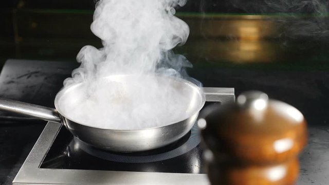 Frying pan with White thick steam in restaurant kitchen. Cooking duck meat. Slow motion. White Water Vapour. Food video. hd
