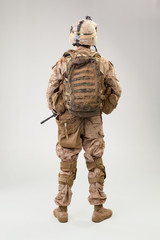 Soldier in US marines uniform with rifle on light grey background, studio shot