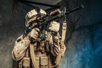American private military contractor shooting a rifle. Studio shot