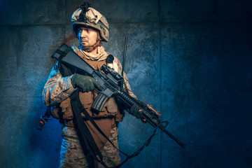 Young man in military outfit a mercenary soldier in modern times on a dark background in studio